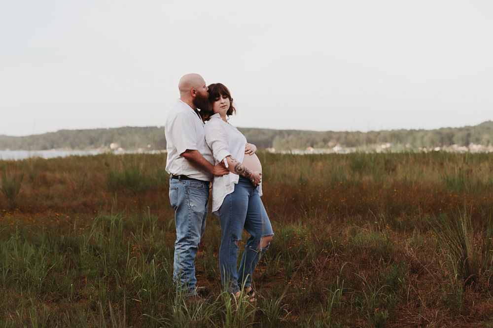 A couple in denim embraces while standing in a rustic autumn field during golden hour.