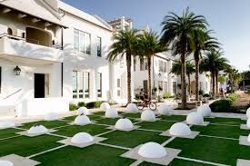Modern white villa with palm trees and manicured lawn featuring contemporary outdoor seating areas and clean architecture.