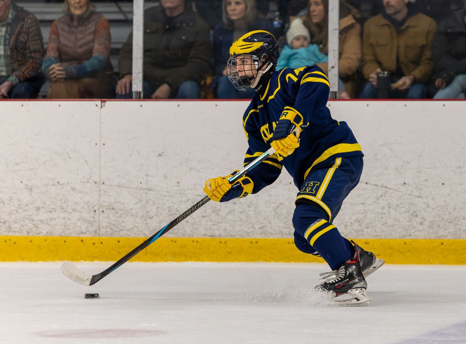 A hockey goalie makes a dramatic save by stretching out across the ice to block the puck.
