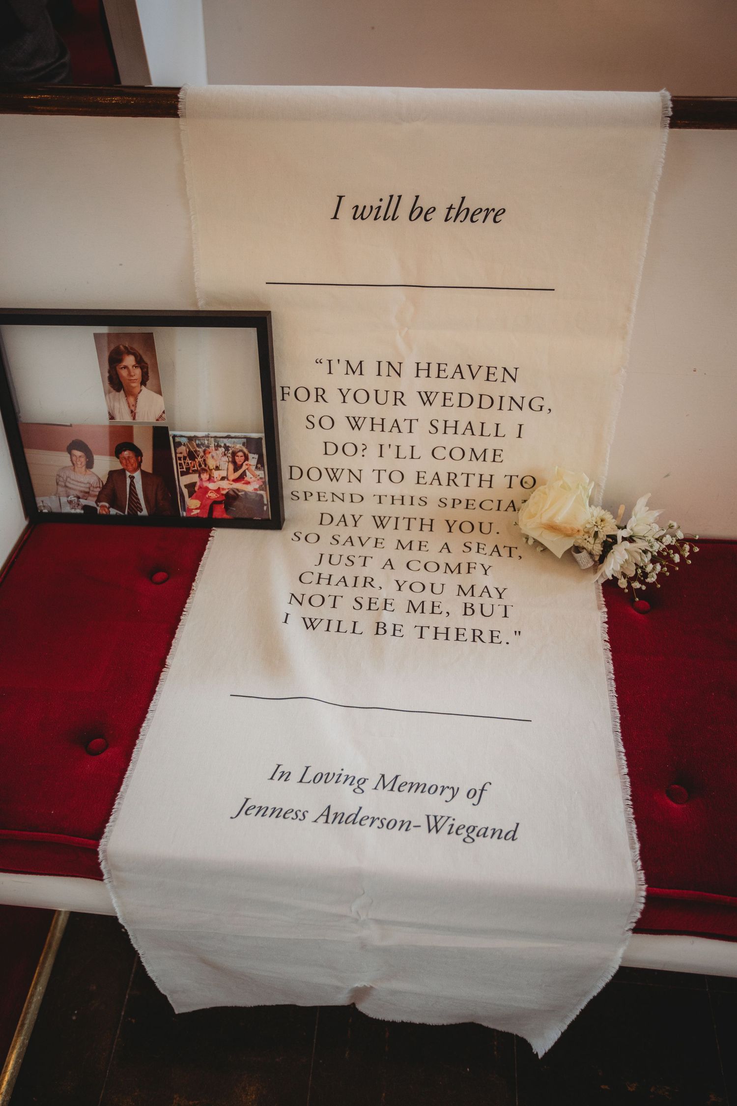 A series of white memorial pillows with embroidered text about being present at a wedding displayed on a red surface.