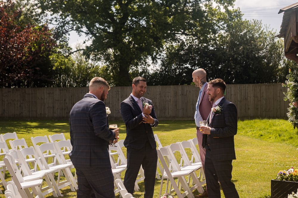 An outdoor wedding ceremony setup with white chairs arranged in rows on a sunny lawn.