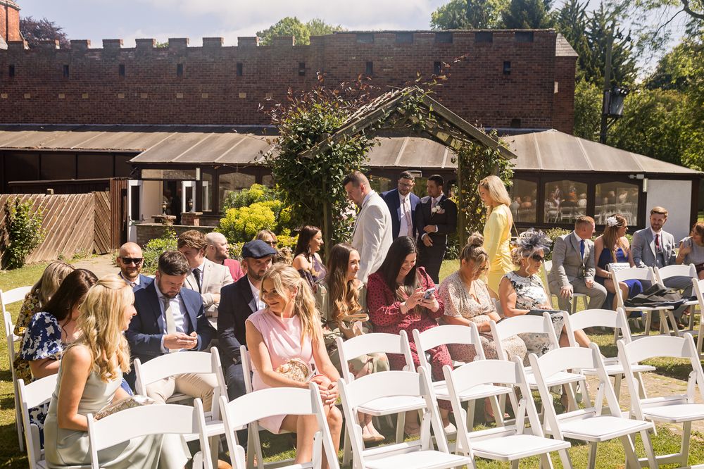 Rows of white folding chairs set up for an outdoor wedding ceremony with a wooden building in the background.