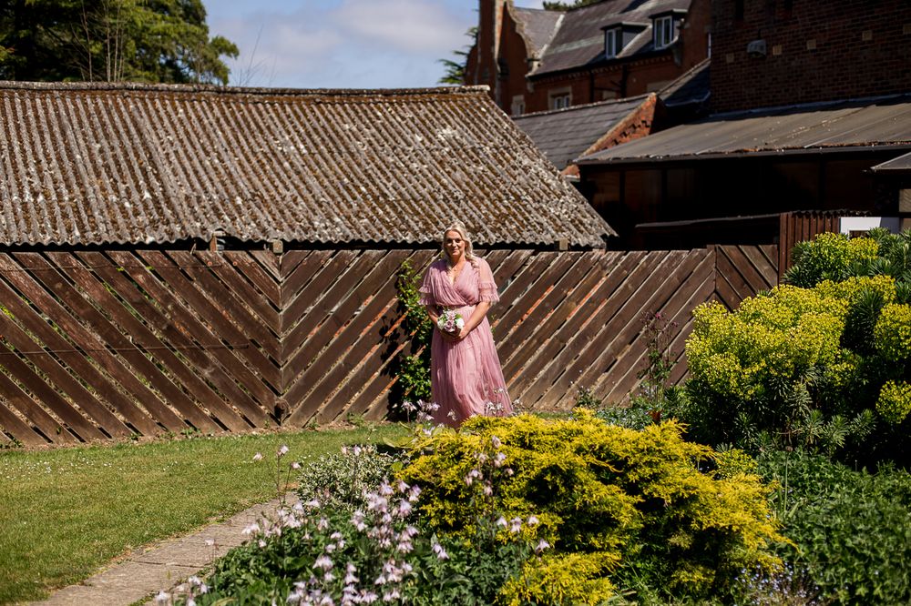 Garden pathway lined with blooming flowers and a rustic wooden fence on a sunny day.