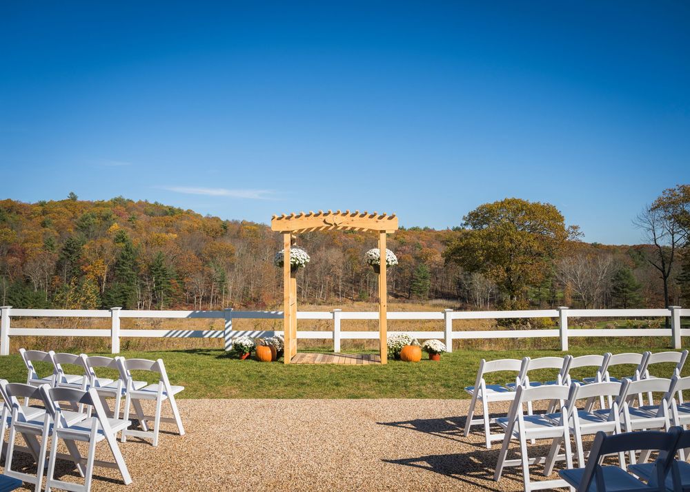 White chairs arranged in rows for an outdoor wedding ceremony with a scenic mountain backdrop and blue sky.