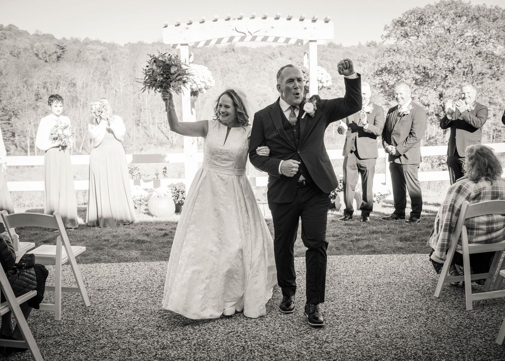 A series of black and white wedding photos showing a couple celebrating joyfully outdoors with guests.