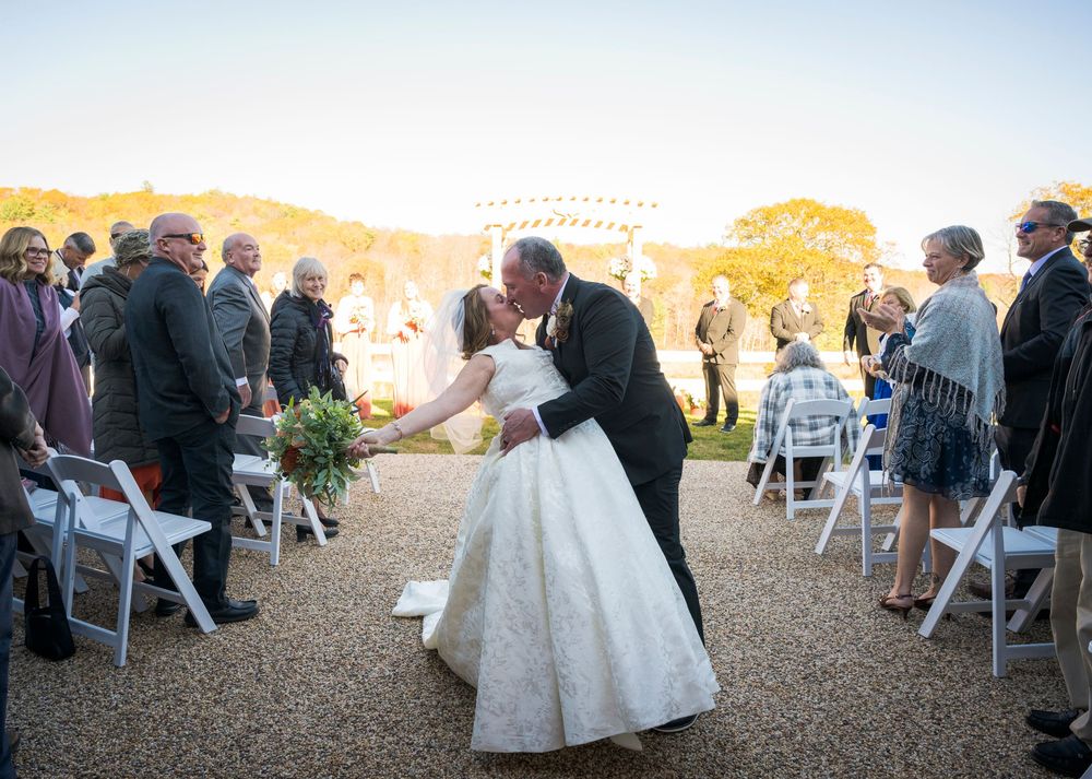 Outdoor wedding ceremony setup at sunset with white chairs and natural landscape.