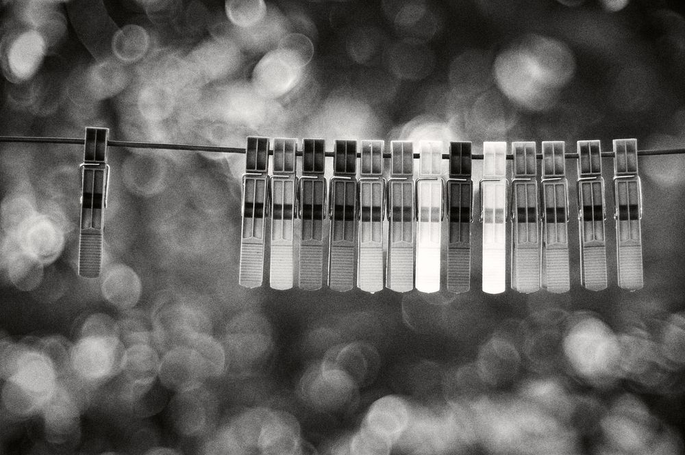 Monochromatic silhouettes of clothes hanging on a clothesline against a blurred bokeh background.