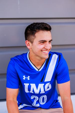 College athlete in blue Under Armour jersey smiles during sports photo session.