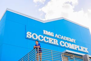 Solar panels installed on the roof of a large soccer complex building with blue sky in the background.