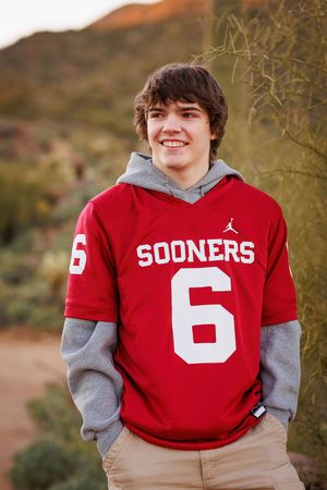 Four sequential photos of someone wearing a red Oklahoma Sooners jersey with the number 6 and grey sleeves against a desert background.