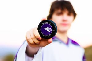 A person holds a purple and black fitness roller against a bright background.