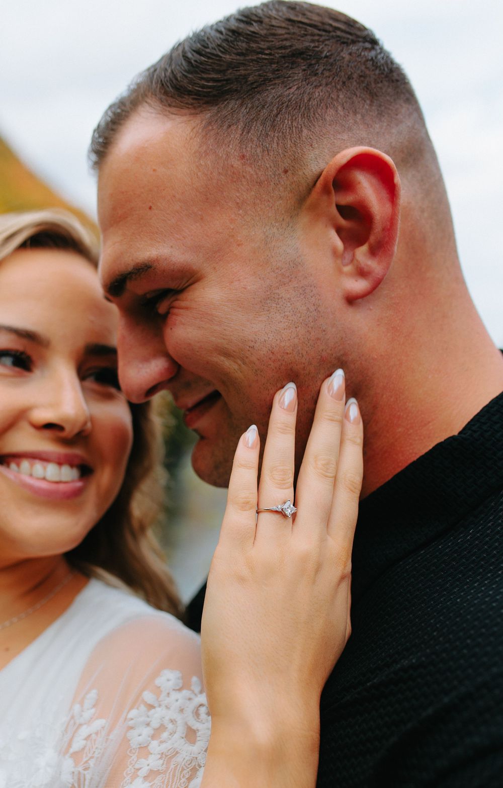 Close-up of a romantic engagement moment showing a sparkling diamond ring and tender smiles between the couple.