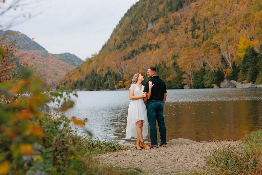 Scenic fall landscape with mountain lake and autumn foliage reflecting in calm waters during golden hour.