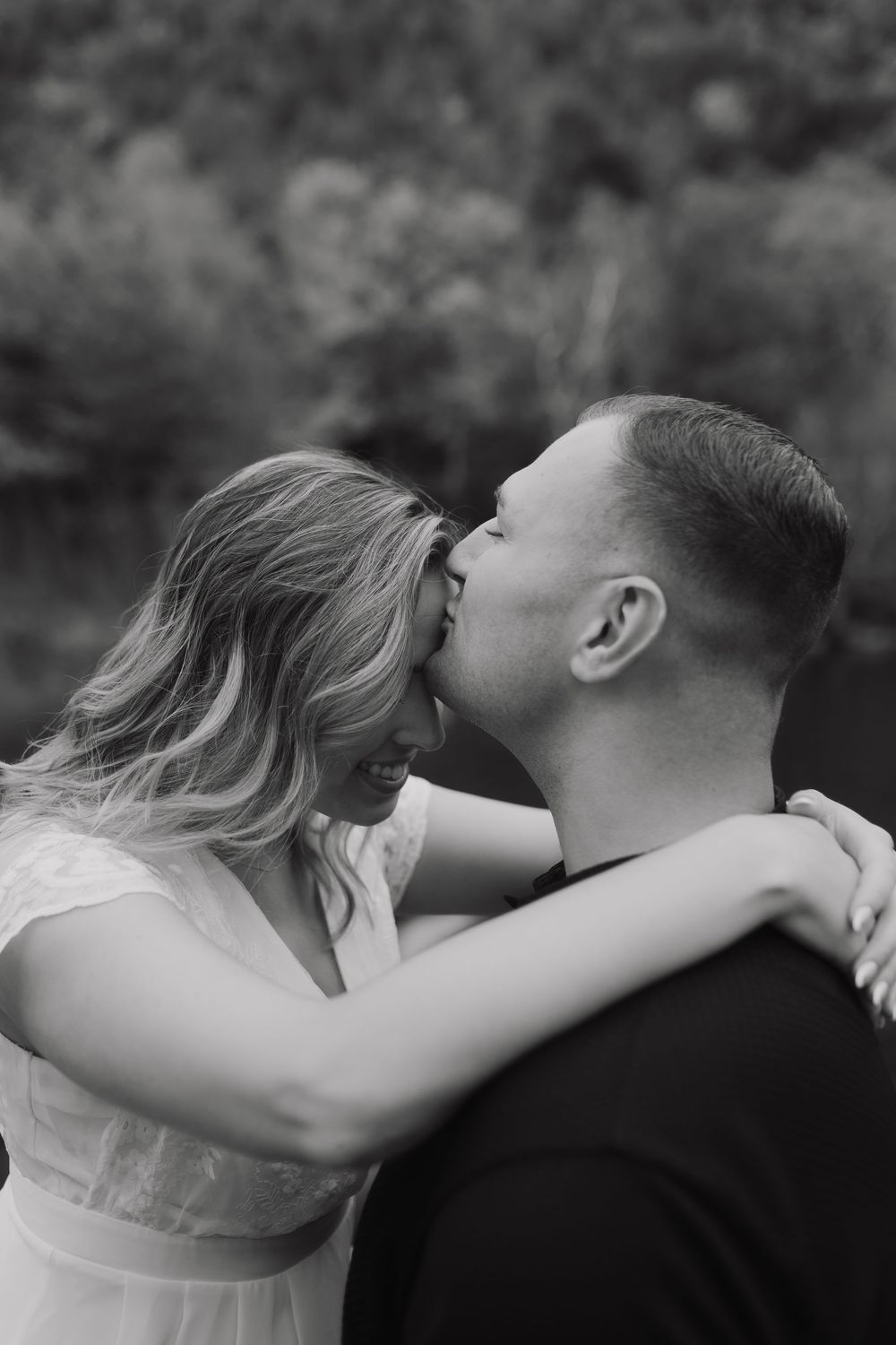 A romantic sequence of black and white photos showing a couple sharing an intimate kiss outdoors.
