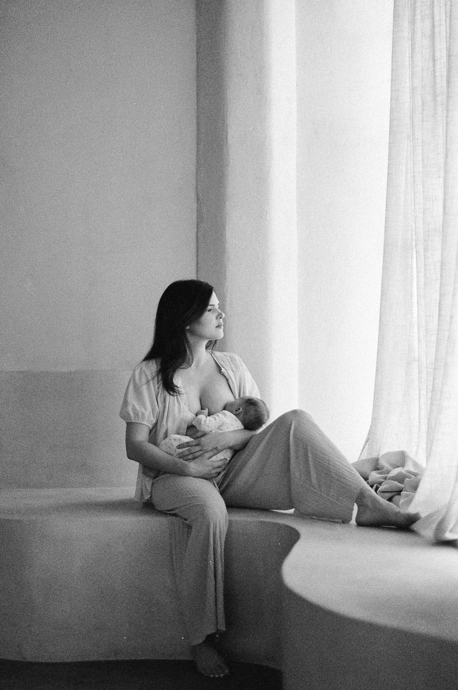 A series of black and white photos showing a person reading by a bright window in different relaxed positions.