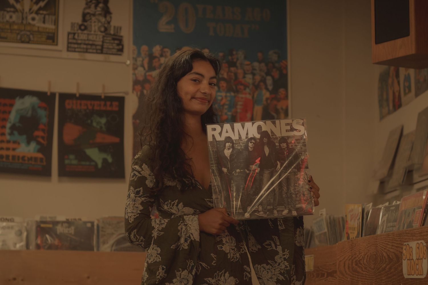 Dark haired senior holding Ramones self-titled album at vinyl store in Easter Washington for portrait session.