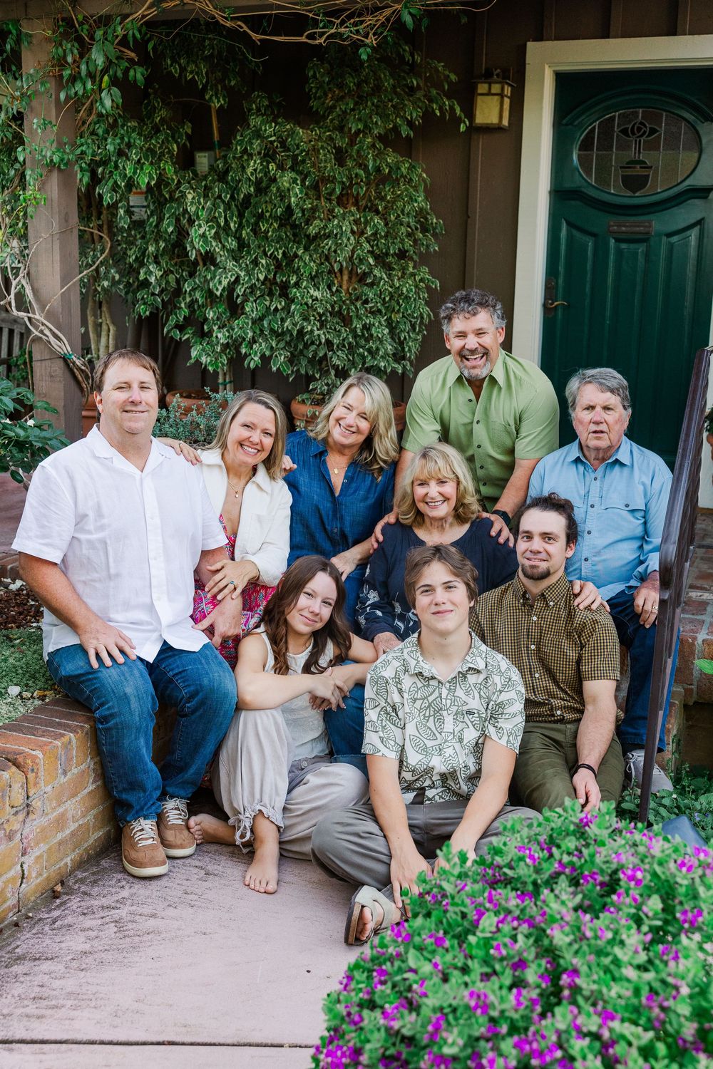 A group of people sitting together on outdoor steps with purple flowers blooming in the foreground.