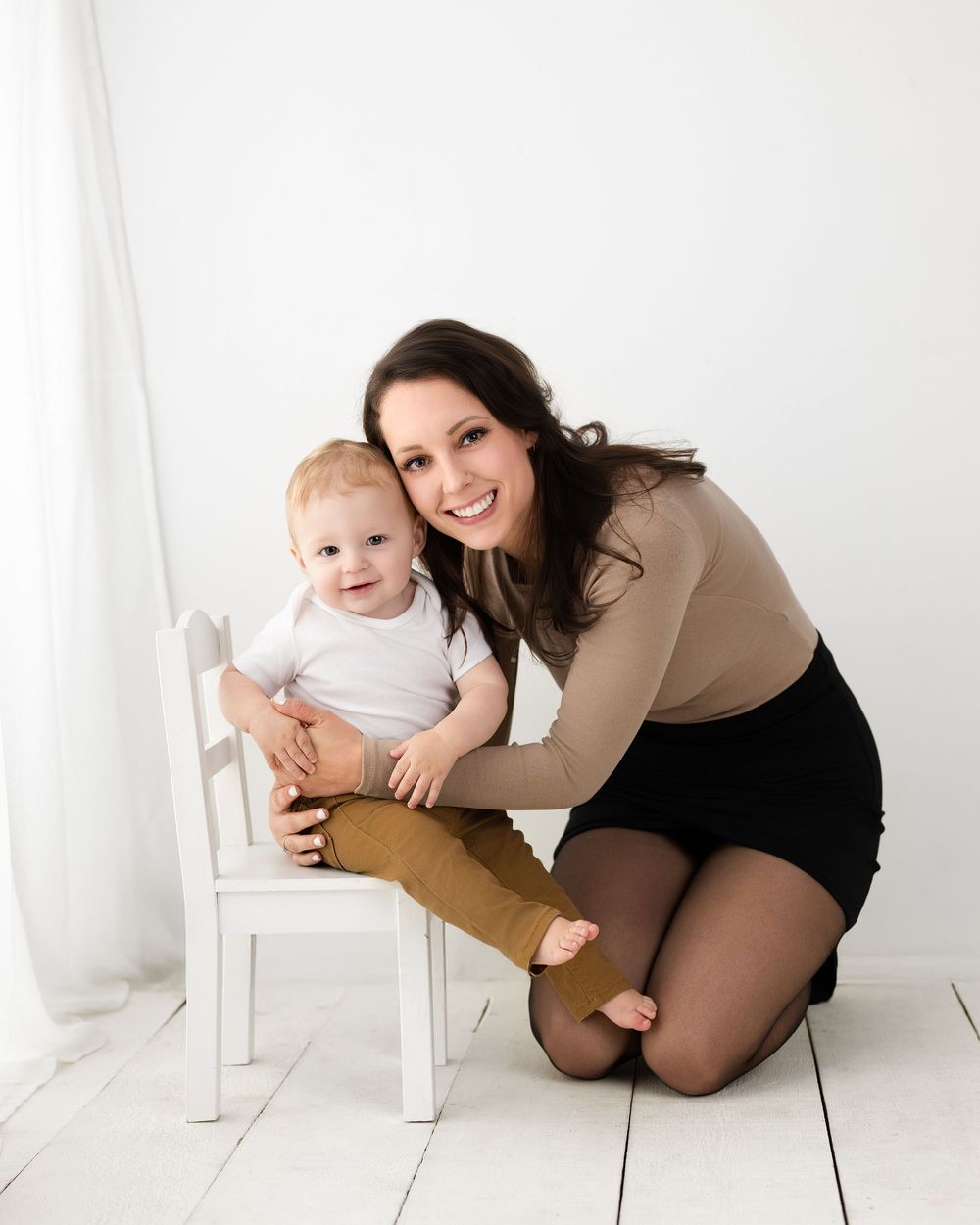 Studio family photoshoot with white chair props and natural lighting.