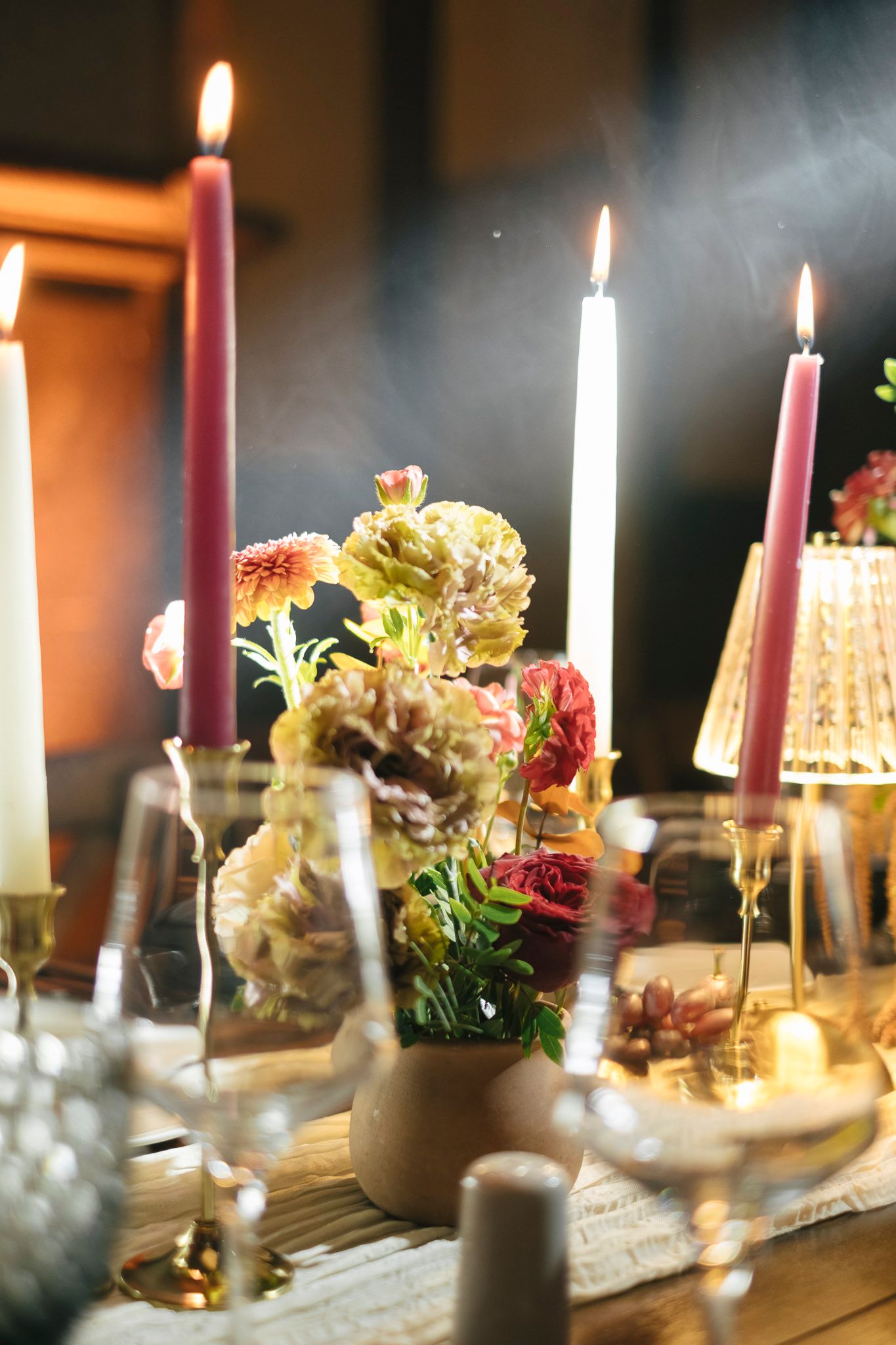 Elegant candlelit table setting with pink taper candles and floral arrangements creating a romantic dining atmosphere.