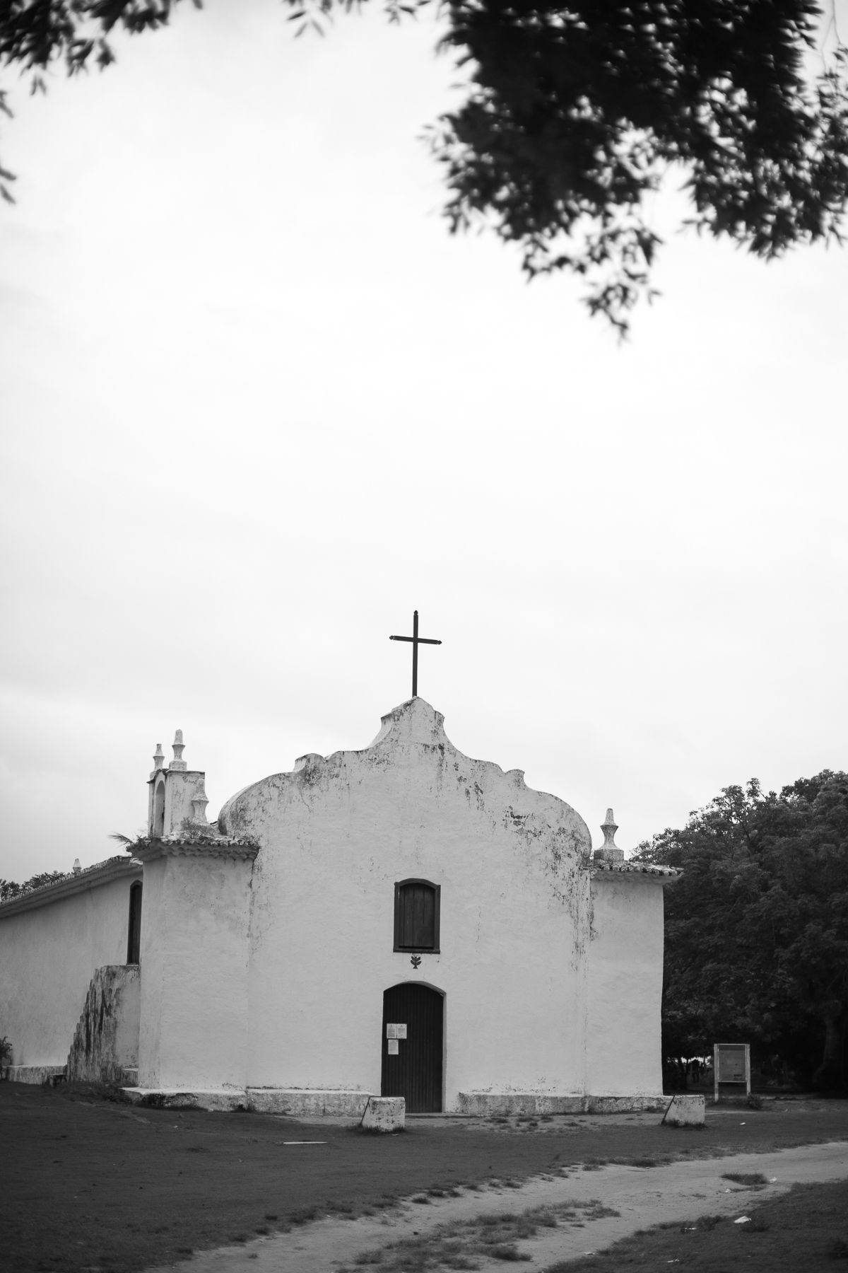 A series of four black and white photos showing a historic white church building with a cross on top from different angles.