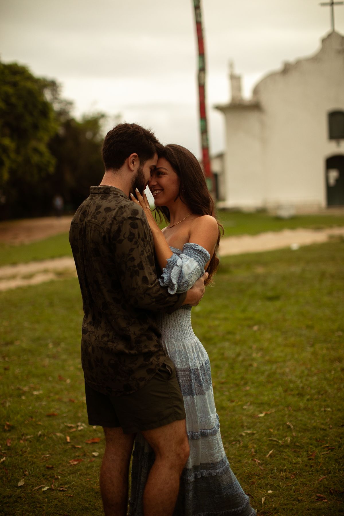 A romantic moment between two people standing in front of a rustic white church.