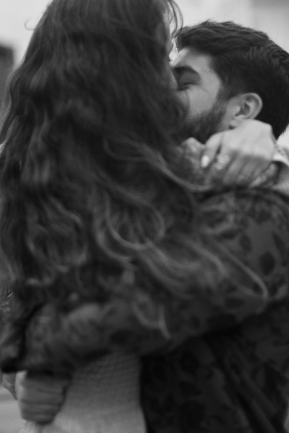 A romantic black and white photograph captures an intimate moment between two people sharing a passionate kiss.