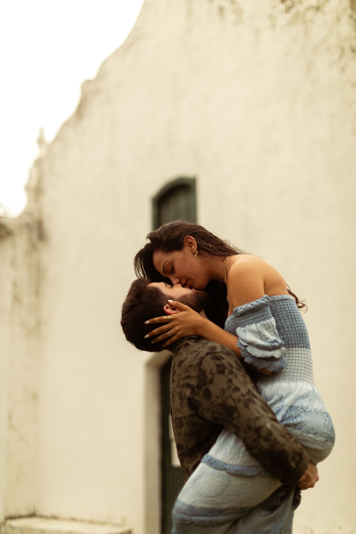 A couple sharing an intimate embrace against a light colored wall in a romantic sequence of photos.