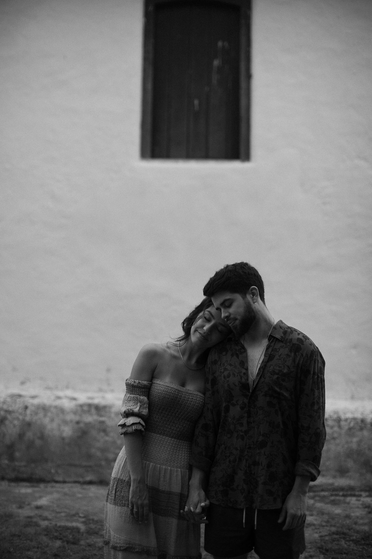 A romantic black and white photo sequence showing a couple embracing and sharing tender moments against a white wall.