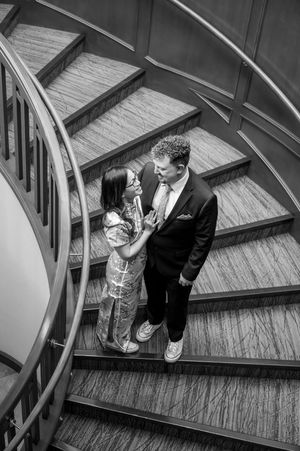 Black and white photo series showing a couple walking down curved stairs at different angles during a wedding.