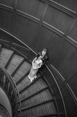 A black and white photo sequence shows a figure ascending a curved spiral staircase in four progressive steps.