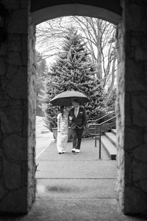 A sequence of black and white photos showing people with an umbrella walking through a stone archway.