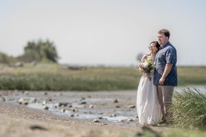 A couple shares a romantic moment together on a scenic beach shoreline during a cloudy day.