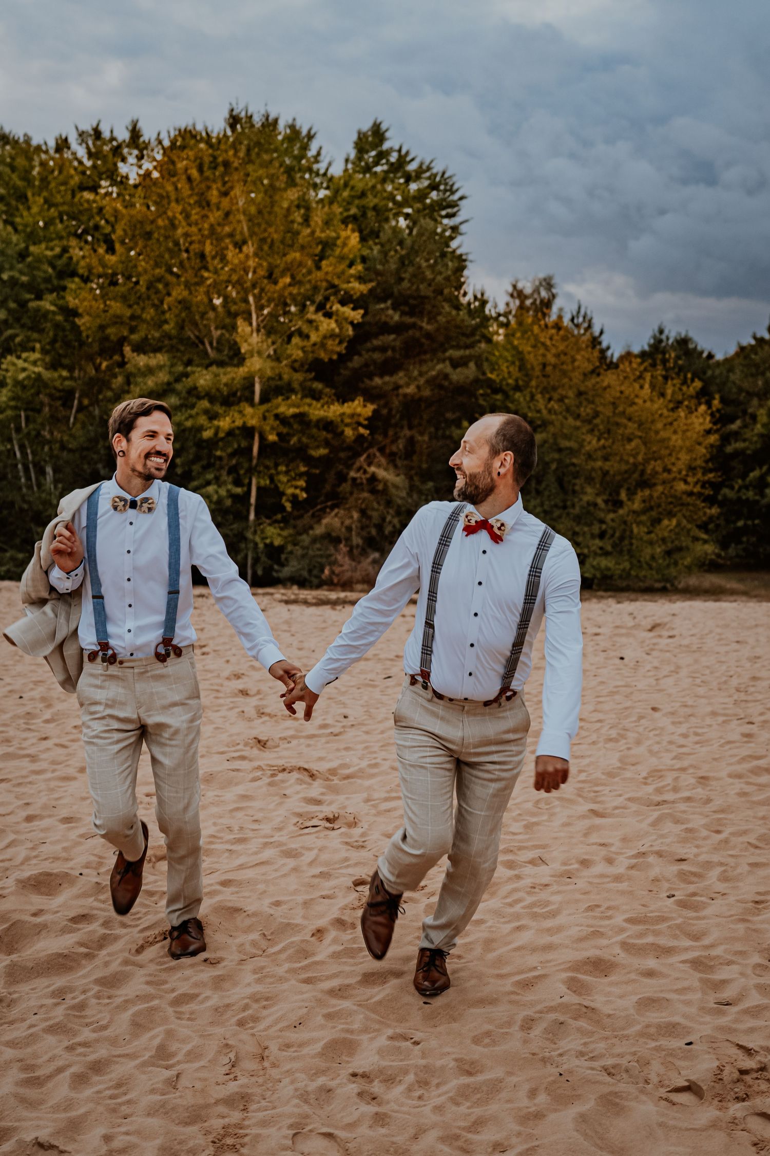 A romantic couple in white clothing shares an intimate moment in a wooded setting during golden hour.