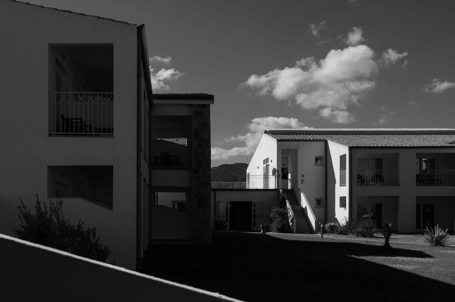Black and white architectural panorama showing a series of modern buildings with clean lines against a cloudy sky.