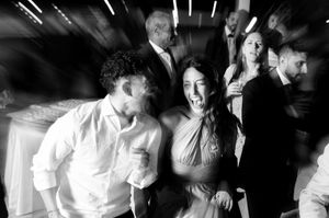 Monochrome panoramic shot of people dancing and socializing at a nighttime celebration.