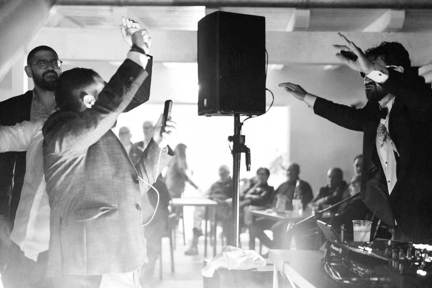 Black and white photo of performers energetically dancing and gesturing on stage during a party or event.