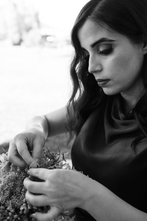 A series of black and white photos showing someone gently holding delicate flowers in a romantic, artistic style.