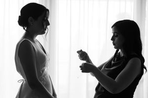 Black and white silhouettes of a couple in a tender embrace against a bright window background.