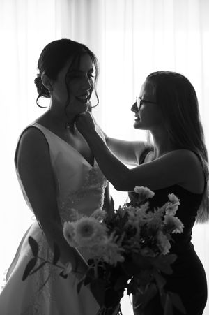 Black and white silhouette of bridesmaids getting ready for a wedding ceremony with bouquets of flowers.