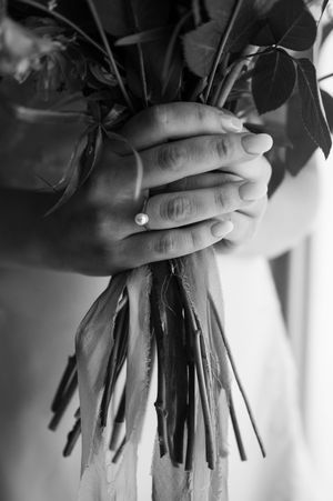Hands gently holding a bouquet of flowers in black and white, creating an intimate and artistic composition.