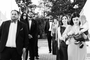 Black and white photo of a formal event with people walking in a line along a garden path.
