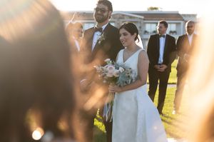 Wedding party walks together outdoors in golden sunlight during sunset celebration.