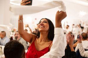 Guests dance and celebrate with raised arms at an energetic wedding reception in an elegant white room.