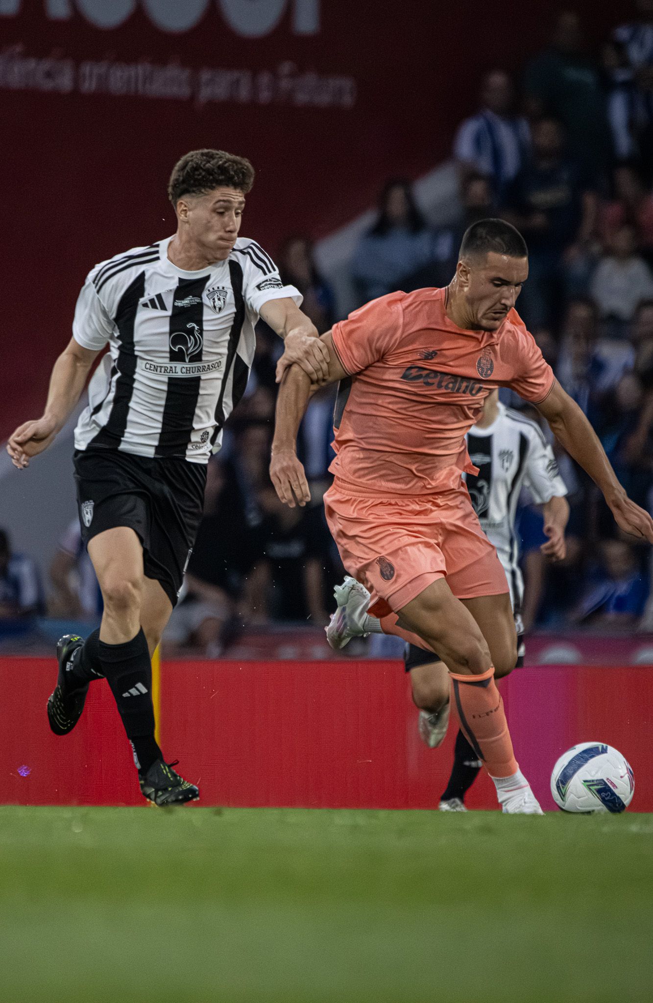 Soccer players in black and white stripes compete against opponents in coral pink uniforms.