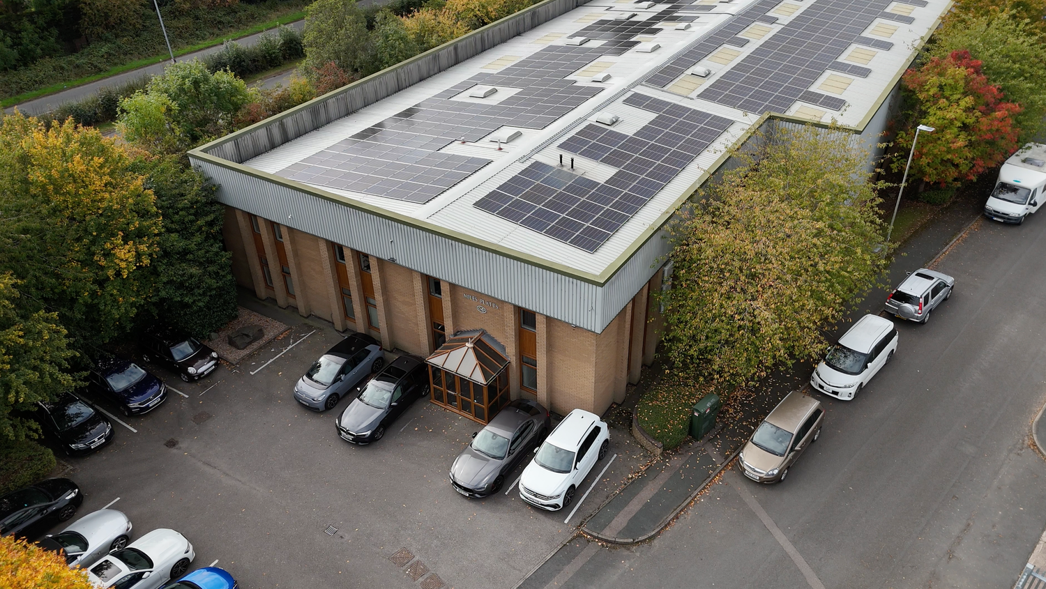 Aerial view of commercial warehouse buildings with white roofs and parking lots in an industrial area.