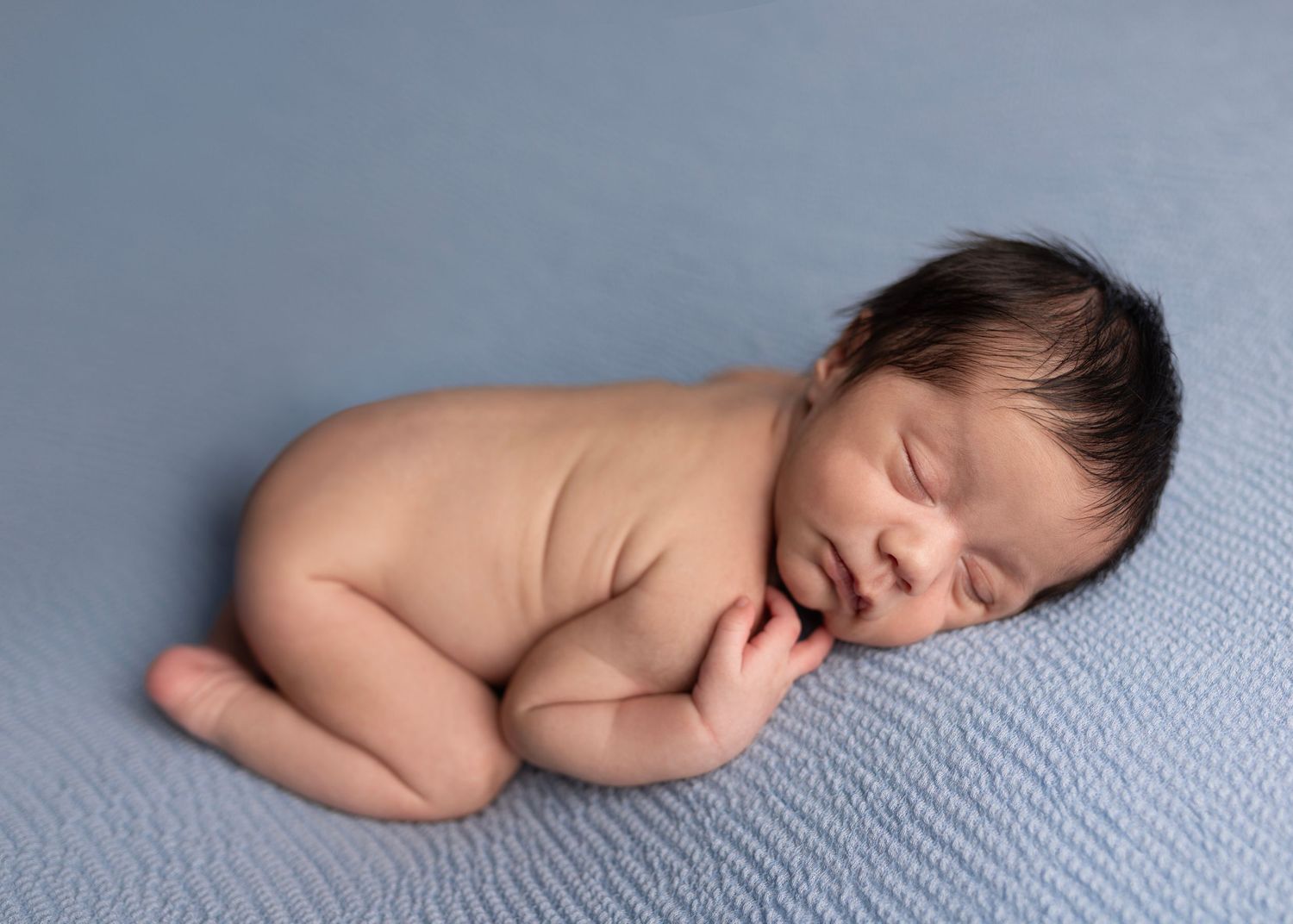 Newborn baby boy poses for newborn photos studio Elizabeth Lang Photography Surrey Cloverdale. Newborn on blue blanket