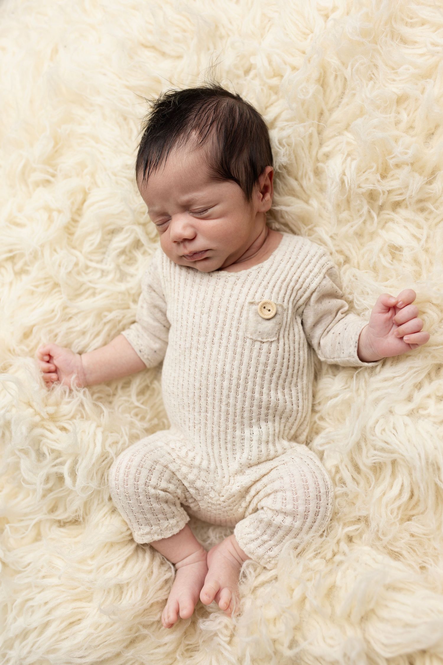 Newborn baby boy poses for newborn photos studio Elizabeth Lang Photography Surrey Cloverdale. On a cream fluffy float blanket