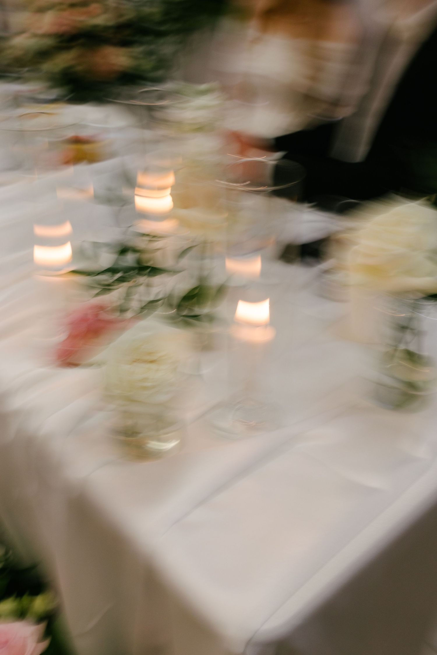 Blurred candlelight and flowers on a reception table.