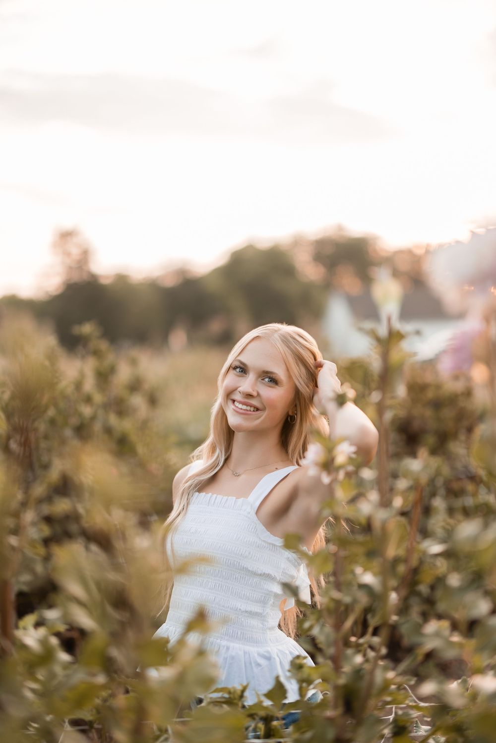 A young person in a white dress twirls joyfully among wildflowers during golden hour at sunset.