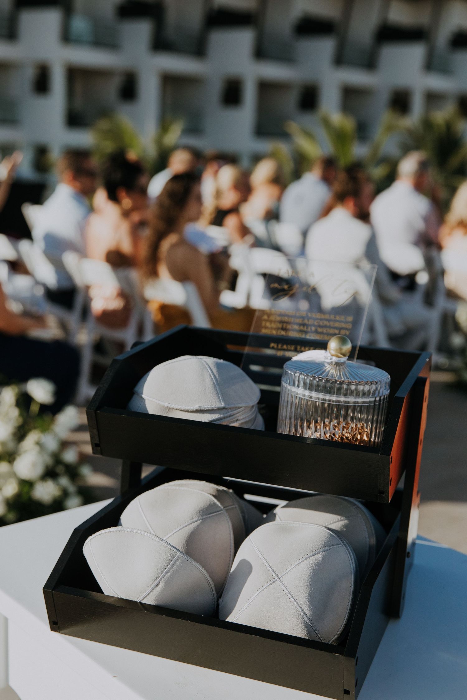 White kippah yarmulkes displayed in tiered black box for Jewish wedding ceremony.